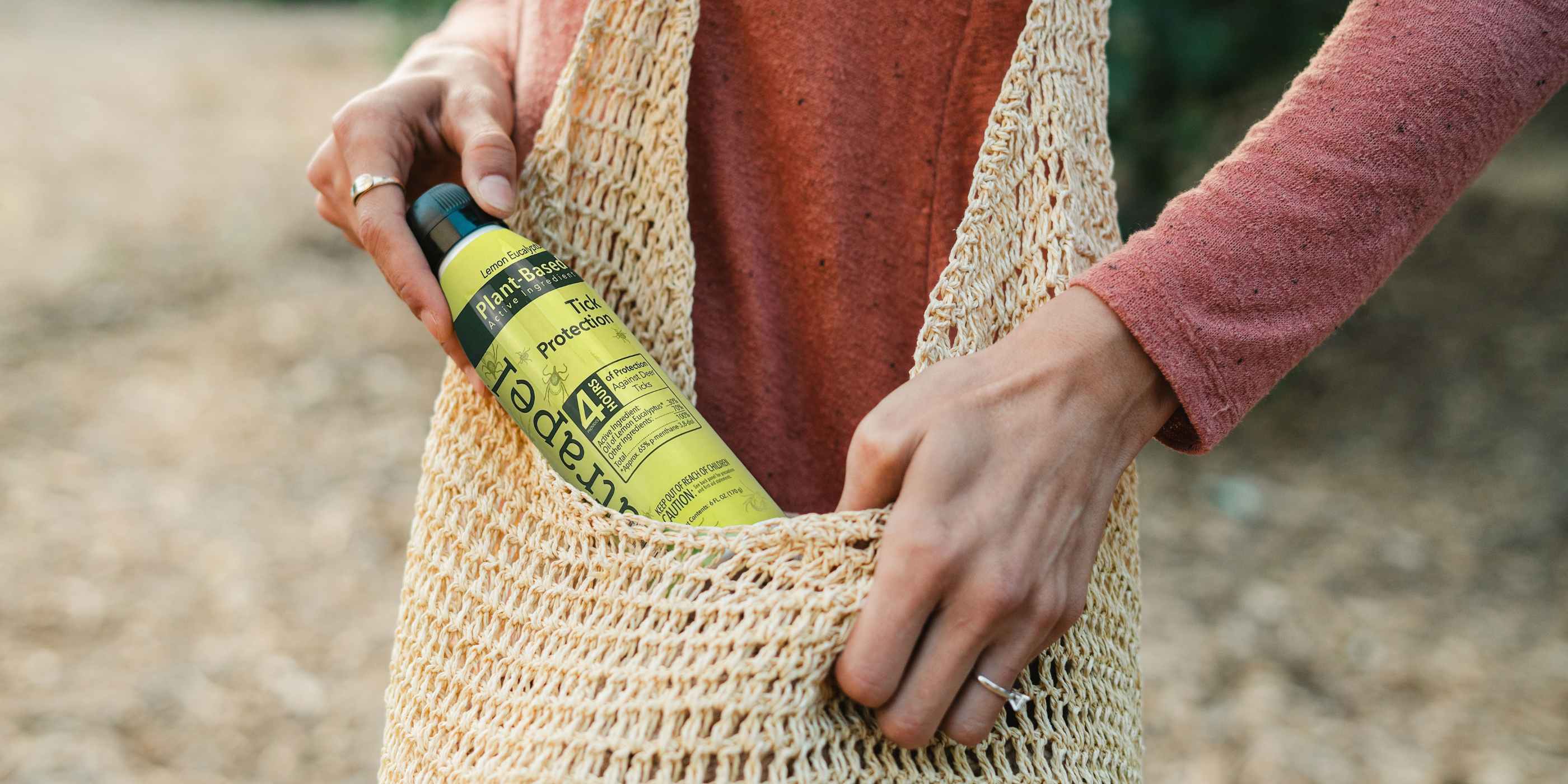 Natrapel Lemon Eucalyptus Tick Repellent being pulled from raffia purse by woman in orange shirt