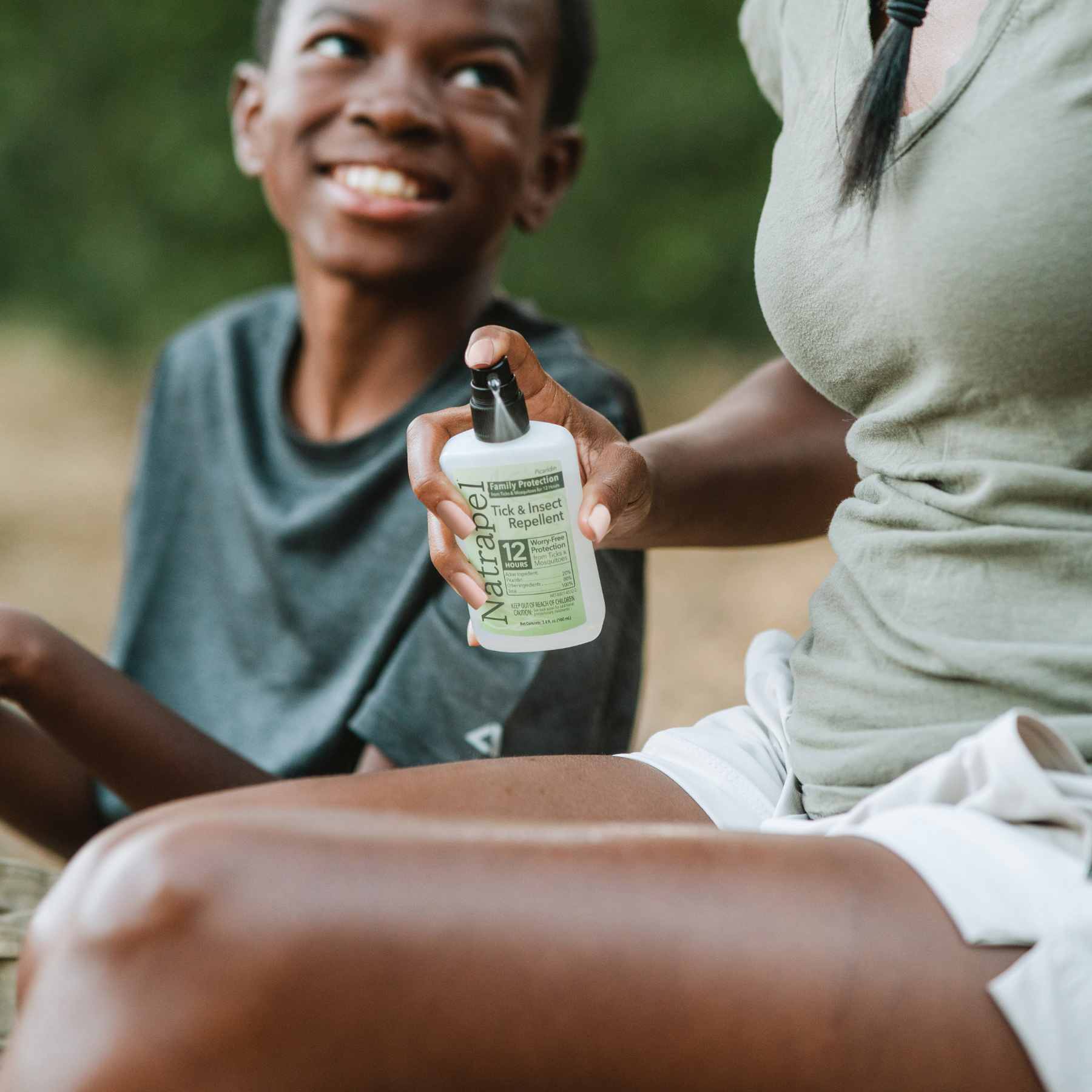 Mother spraying Natrapel Picaridin 3.4 oz Insect Repellent on leg next to son