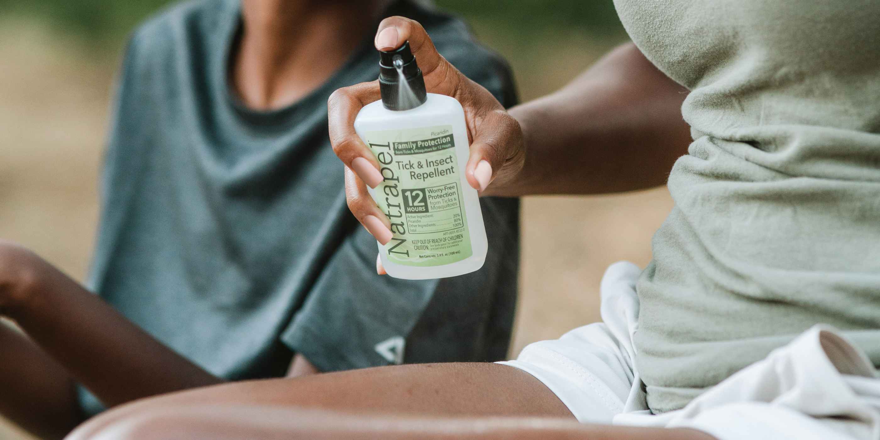 Mother spraying Natrapel Picaridin 3.4 oz Insect Repellent on leg next to son