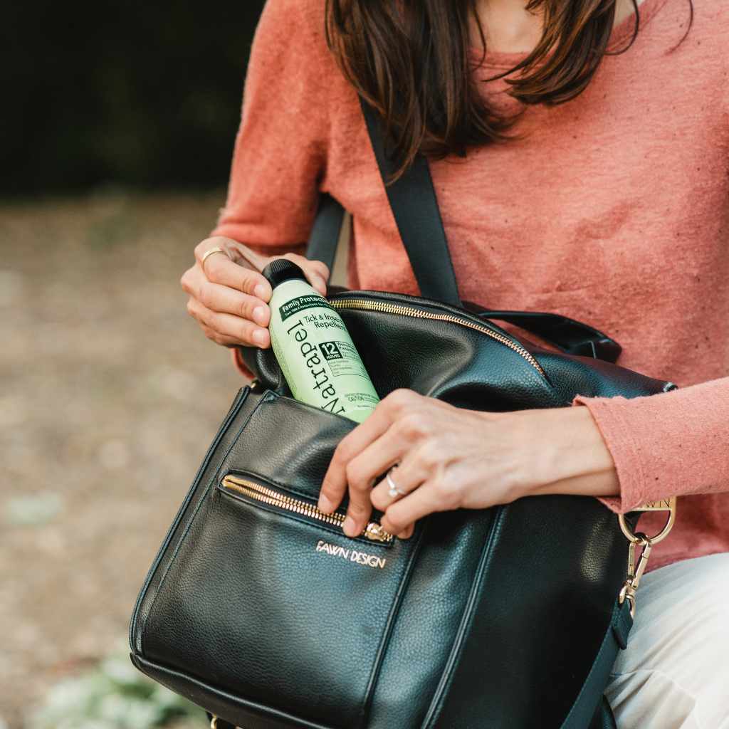 Natrapel Picaridin Tick & Insect Repellent Eco-Spray 6 oz. woman pulling out of black bag that says Fawn Design