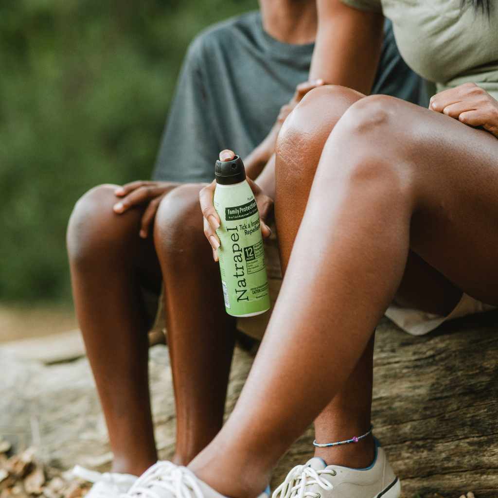 Natrapel Picaridin Tick & Insect Repellent Eco-Spray 6 oz. person spraying on leg while seated next to child