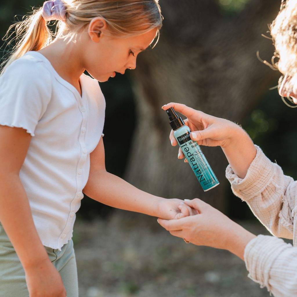 Woman applying the Natrapel Essential Oil Insect Repellent spray to a child's arm