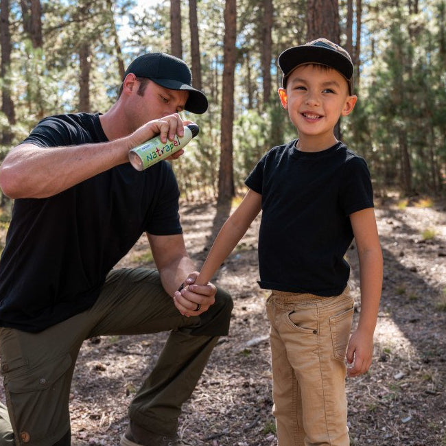 child being sprayed with insect repellent by an adult